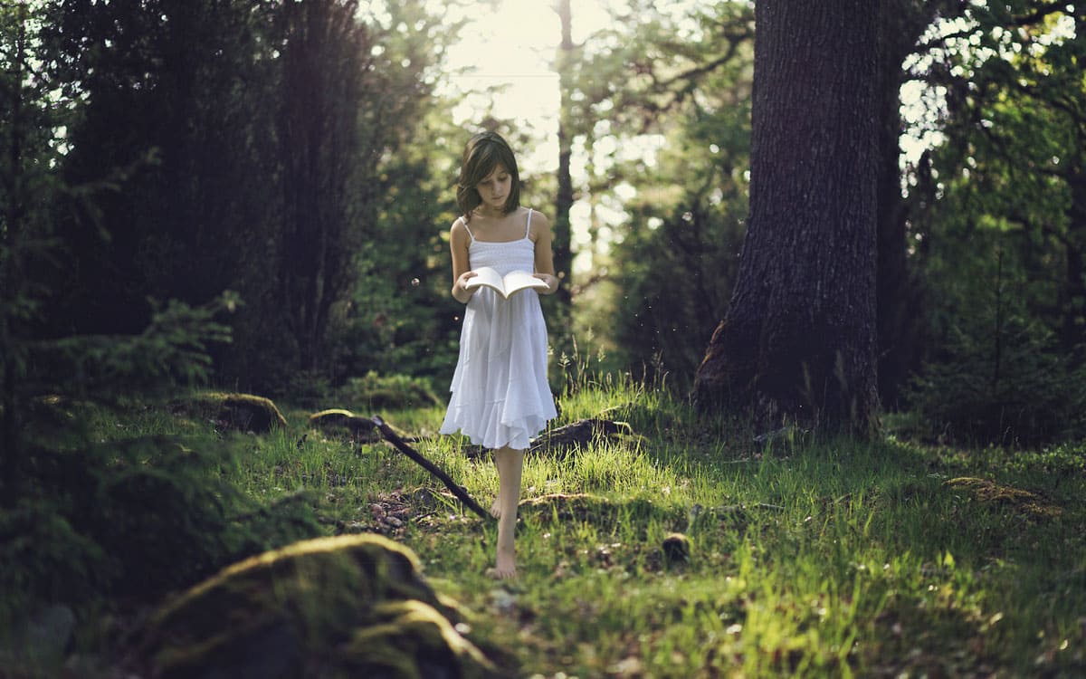 Niña leyendo en el bosque