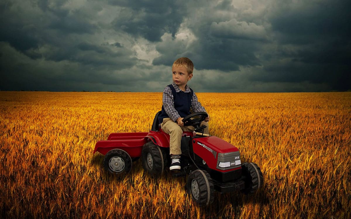 Niño montado en tractor de juguete en el campo